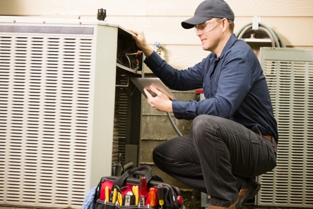 Air conditioner repairman works on home unit.